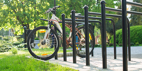 A bicycle parked at a bike rack with a lush forest behind.